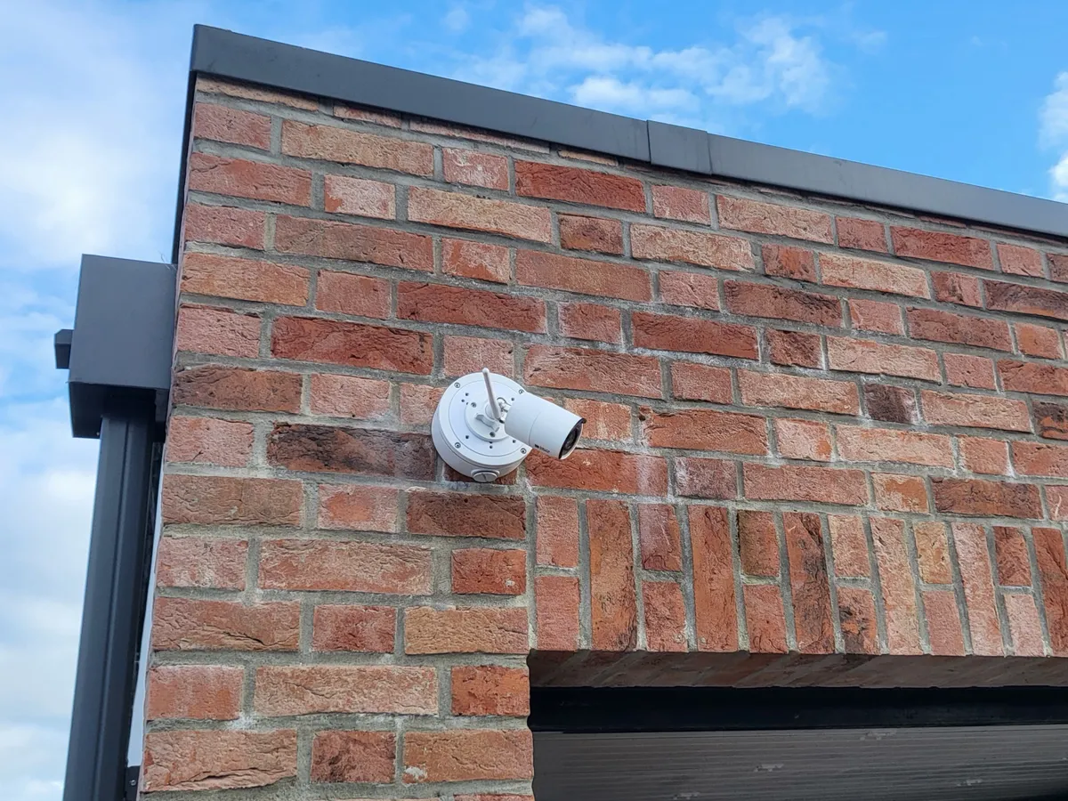 Caméra de surveillance extérieure installée sur une façade en briques.